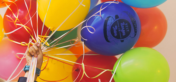 Mehrere bunte Luftballons sind mit einem Logo bedruckt